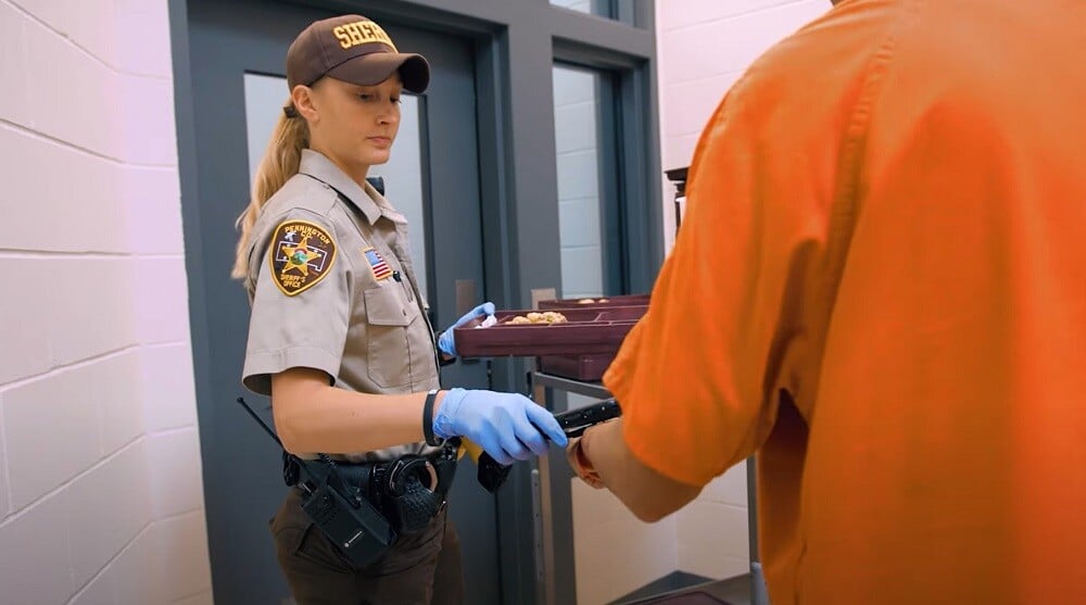 officer scanning wristband to pass meal tray