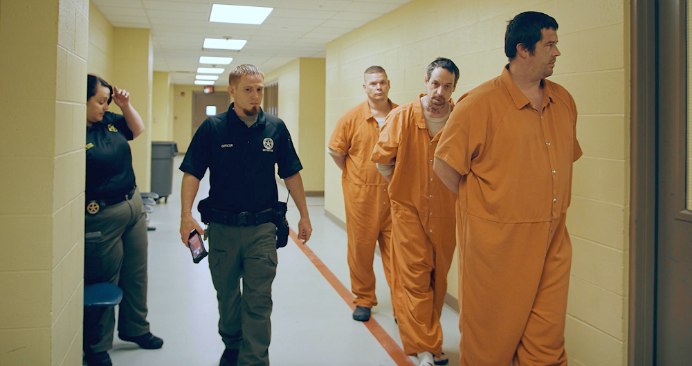 corrections officer walking with SPARTAN and restrained high risk inmates